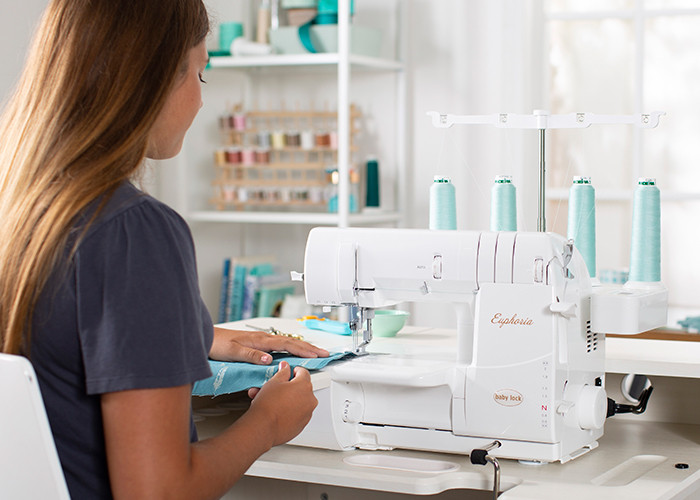 A maker sitting at the Baby Lock Euphoria Cover Stitch serger using the machine. 